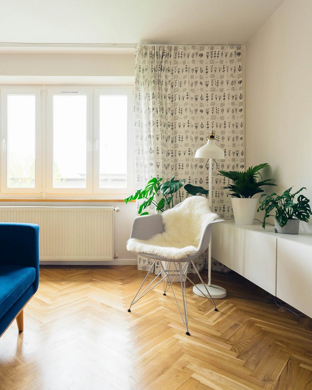 Světlý obývací pokoj moderního pražského bytu s parketovou podlahou a velkými okny